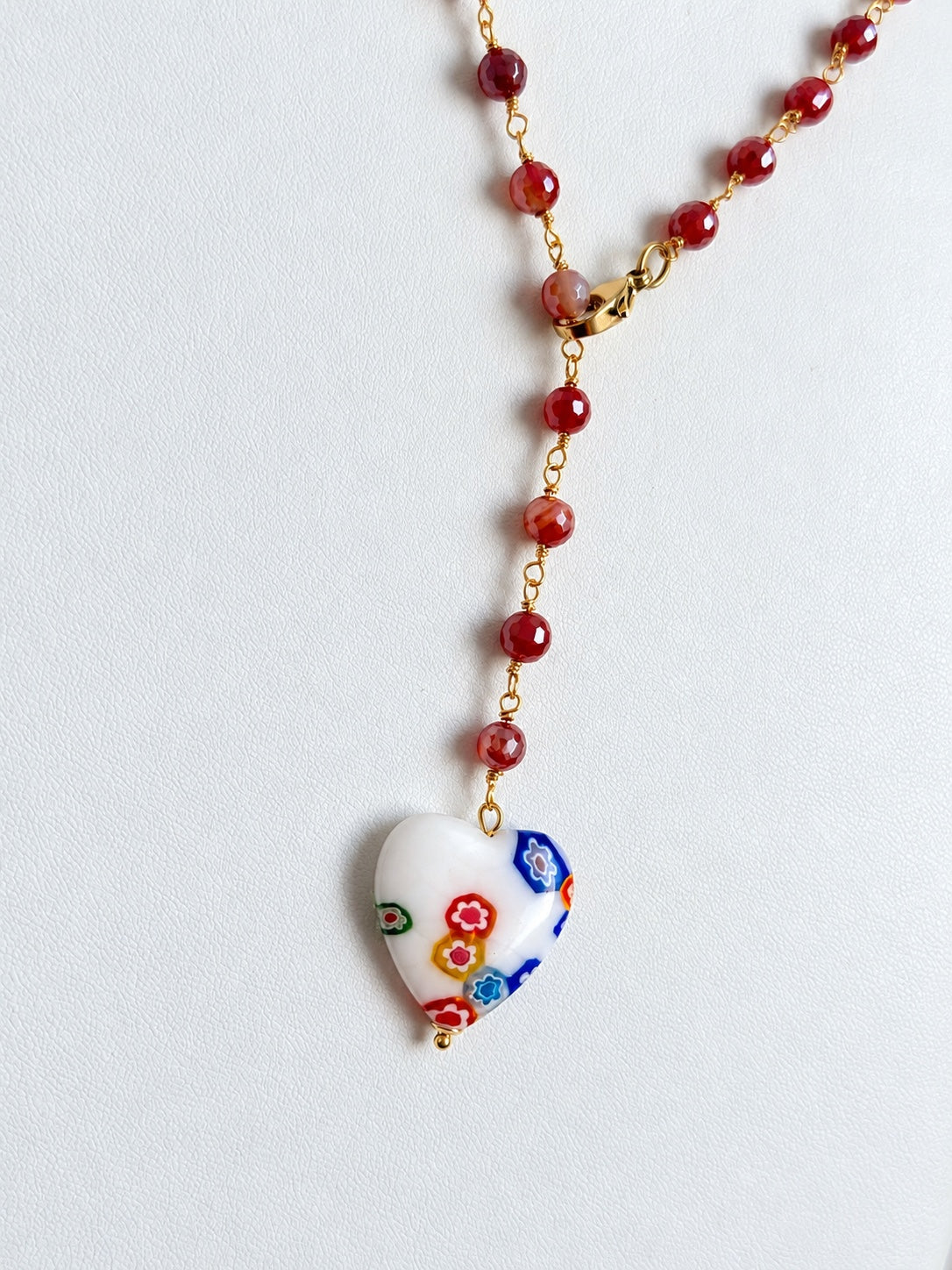 Dettaglio del cuore in vetro bianco decorato e delle pietre di corniola